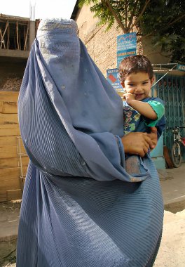 Afganistan 'da Kabil. Afganistan, Kabil 'de bir çocuğu tutan mavi burka (burka) giymiş bir kadın. Kabil Afganistan 'ın başkentidir. Anne, çocuk, burka, burka, Kabil, Afganistan.