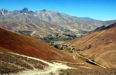 Afganistan 'da Kabil ve Bamyan (Bamiyan) arasındaki dağ manzarası. Uzak bir köye giden tozlu bir yol. Afganistan 'ın orta kesiminde Kabil ve Bamyan (Bamiyan) arasındaki güney yolunda çekildi..