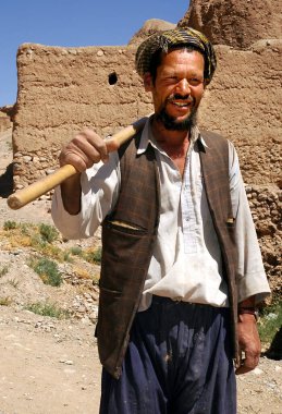Orta Afganistan 'da Bamyan (Bamiyan). Afganistan 'daki Bamyan (Bamiyan) işine giderken bir adam yanında kürek taşır. Bu Afgan adam Afganistan 'daki Bamyan (Bamiyan) Buda' larına yakın..