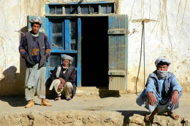 Bamyan (Bamiyan) ilindeki Syadara (Siyah Darah), Afganistan. Orta Afganistan 'daki Syadara kasabasında bir evin önünde türbanlı üç Afgan adam. Afganistan 'da bir köyde.