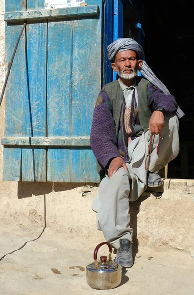 阿富汗巴米扬省的Syadara Siyah Darah 在阿富汗中部的西亚达拉小镇 一名阿富汗人坐在门口 戴着头巾 珠子和茶壶的男人 — 图库照片