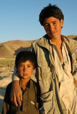 Ghor Eyaleti, Afganistan 'daki Dowlat Yar. Orta Afganistan 'da Dowlatyar yakınlarında genç bir çocuğu kollarıyla saran genç bir Afgan' ın portresi. Tepelerin arkaplanı.