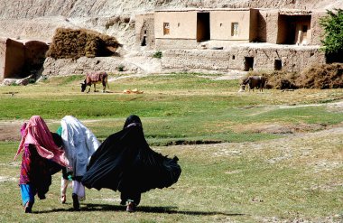 Afganistan 'ın Ghor Eyaleti' ndeki Chaghcharan ve Jam Minaresi arasında küçük bir köy. Yerel kıyafetli üç genç kadın Orta Afganistan 'ın ücra bir köşesindeki evlerine doğru koşuyor..