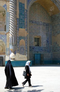 Balkh Eyaleti, Afganistan. İki geleneksel kadın, Afganistan 'ın kuzeyindeki Balkh kentindeki Khwaja Abu Nasr Parsa Tapınağı' nın (Yeşil Cami) antik süslü kapısının önünden geçiyor..
