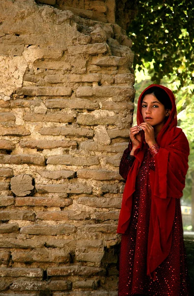 阿富汗巴尔赫省巴尔赫 在阿富汗北部巴尔赫 一名身穿闪亮红色衣服的传统阿富汗女孩站在砖墙边 穿着传统服装的漂亮阿富汗女孩 — 图库照片