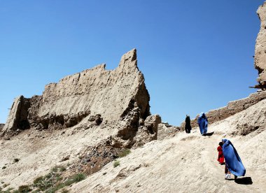 Afganistan 'da Gazni. Kadınlar ve kızlar Gazni Kalesi 'nin duvarından geçtiler. Kadınlar, Orta Afganistan 'da geleneksel olarak kullanılan mavi burka (burka) giyiyorlar. Yerel giysili Afgan kadınlar Gazni.