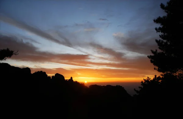 黄山安徽省 中国で カラフルな空と雲 山と前景の木のシルエットと山の上の日没 黄山の頂上付近の日没 — ストック写真