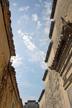 Çin 'in Anhui eyaletindeki Xidi Antik Kasabası. Eski Xidi kasabasındaki çatılar ve beyaz duvarlar bulutlu mavi bir gökyüzüne karşı kurulmuştu. Çin 'in tarihi Xidi kasabasındaki eski çatıların döşemeleri ve saçılmaları.. 
