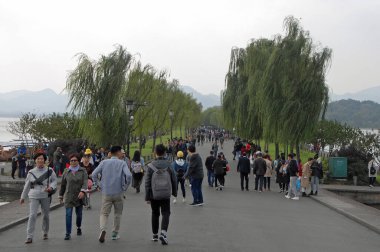 Batı Gölü (Xi Hu) Hangzhou, Zhejiang ili, Çin. Baidi Geçidi. Söğüt ağaçları ve yürüyen insanlar..