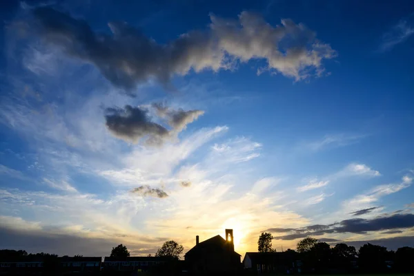 イギリスのケント州ベッケンハムにあるセントジョンズ教会の日没時の劇的な雲 夕日は教会の鐘楼を通して輝いています 教会のシルエットで夕日の美しい雲と夜の空 — ストック写真