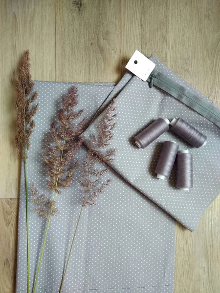 Gri kumaş. İplik ve fermuarla.