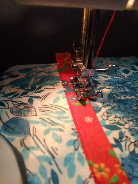 Sewing machine. Blue fabric with a red ribbon.