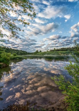 Sabahın erken saatlerinde Ugra nehrinde. Güneşle aydınlanan bulutlar, sudaki yansıma, kıyıda süzülen hafif sis..