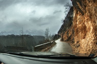 Balkanlar 'daki tehlikeli dağ yolu. Sağdaki dik yamaçta, soldaki yamaçta. Arabanın ön camında yağmur damlaları var..