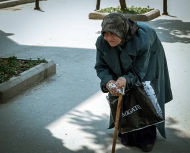 Bükreş / Romanya - 05.01.2019: Yürüme sopasıyla kambur yaşlı kadın. Bükreş 'te yemek için yalvaran yaşlı kadın..