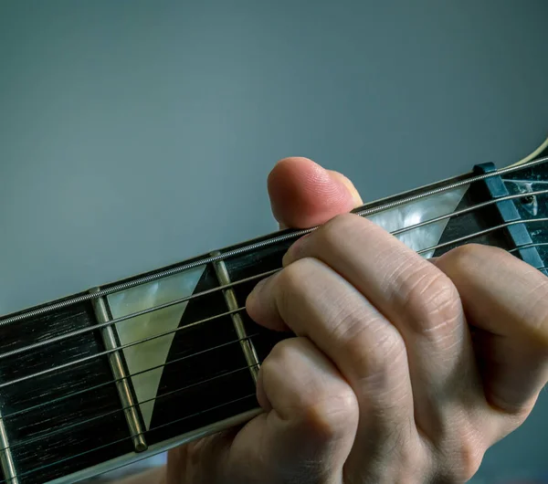 Finger in position of E minor chord. Hand holding a guitar .