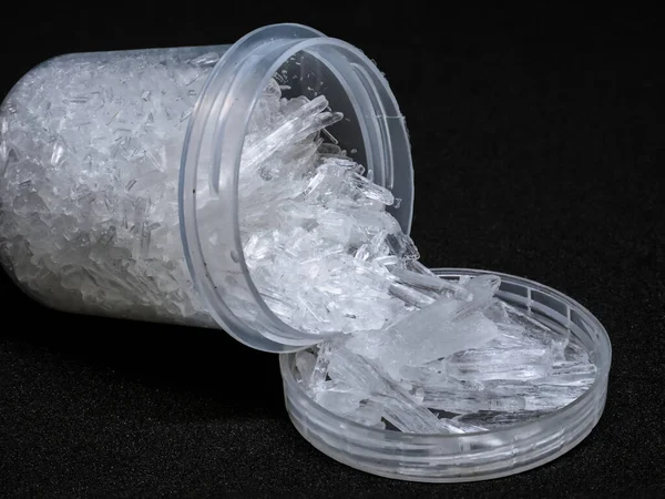 Siyah arka planda doğal mentollü kristaller. Mentollü kristallerle doldurulmuş küçük plastik alıcı.