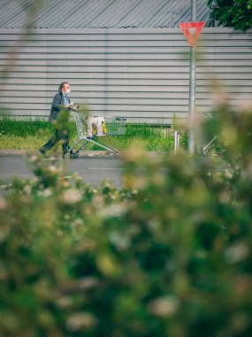 Bükreş / Romanya - 05.01.2020: Yüzü maskeli bir adam içi çanta dolu bir alışveriş arabasını itiyor.