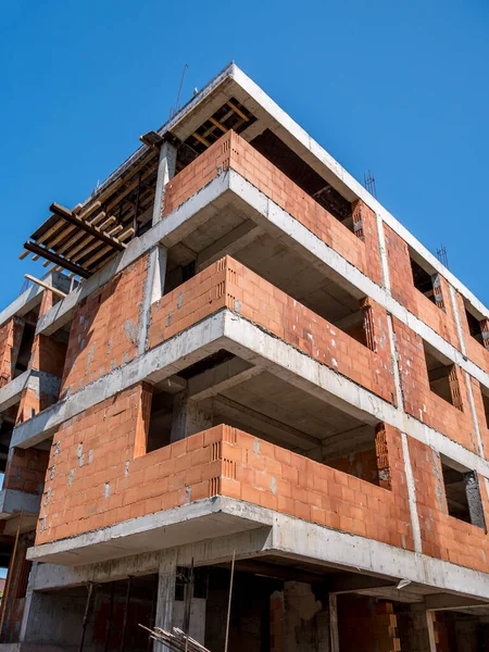 Apartment buliding under construction. Unfinished construction bulding against blue sky.