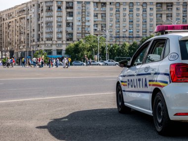 Bükreş / Romanya - 05.17.2020: Hükümet tarafından alınan koronavirüs tedbirlerini protesto etmek üzere toplanan Piata Victoriei Meydanı 'ndan göstericileri yakından denetleyen polis arabaları