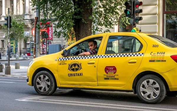 Bükreş / Romanya - 05.16.2020: CRISTAXI 'ye ait bir arabada taksi şoförü kameraya bakıyor. Şoför kameraya bakıyor..