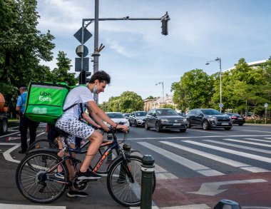 Bükreş / Romanya - 05.17.2020: Uber trafik ışığında kurye yiyor. Emri teslim eden genç bir yetişkin.