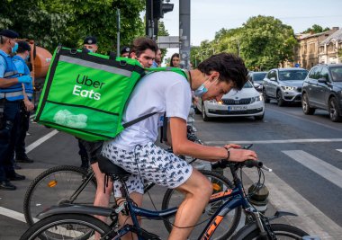 Bükreş / Romanya - 05.17.2020: Uber trafik ışığında kurye yiyor. Emri teslim eden genç bir yetişkin.