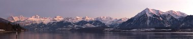Thun Gölü 'nün panoramik manzarası ve ünlü Jungfrau sıradağları ve gün batımında Niesen.