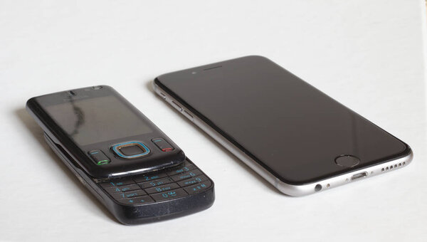Берн, Швейцария, февраль 2019 года: старый телефон Nokia рядом с новым iPhone 7 на белом фоне.