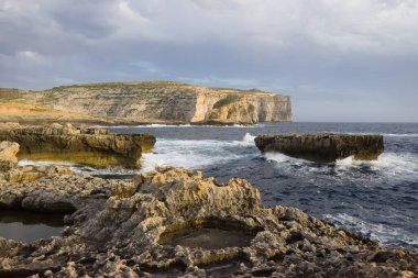 Gozo, Malta 'daki Dweira Körfezi' nde kayalıkların, mantar kayalarının ve mavi okyanusun manzarası..