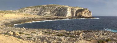 Gozo, Malta 'daki Dweira Körfezi' nde kayalıkların, mantar kayalarının ve mavi okyanusun manzarası..