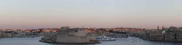 Gün batımında St. Angelo Kalesi 'nde Vittoriosa' daki Grand Harbor 'da gün batımında, Malta. Şehrin siluetine vuran son ışık.