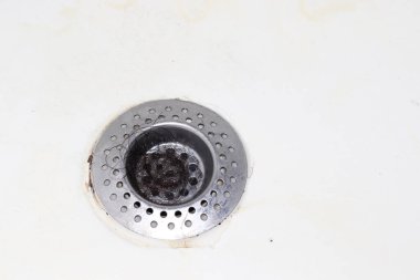 siyah saç kümesi metal bir küvet ya da banyo giderine sıkışmış..
