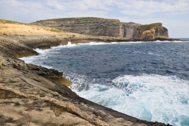 Gozo, Malta 'daki Dweira Körfezi' nde kayalıkların, mantar kayalarının ve mavi okyanusun manzarası..