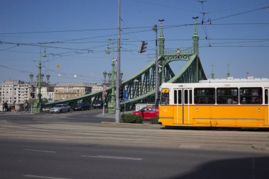 Budapeşte, Macaristan 'daki Özgürlük Köprüsü' nün önünden geçen sarı tramvay..