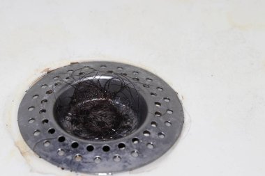 siyah saç kümesi metal bir küvet ya da banyo giderine sıkıştı..