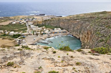 İç denizlere bakan, yanında küçük evler ve arka planda Gozo, Malta 'da bulunan mantar kayaları..