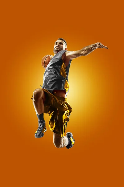 Яркий профессиональный баскетболист на оранжевом фоне — стоковое фото