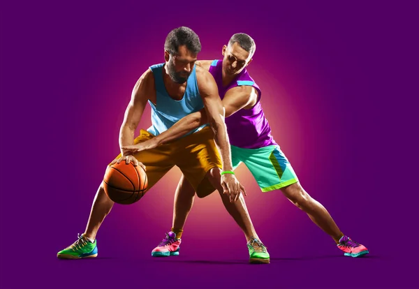 Coloridos jugadores profesionales de baloncesto aislados sobre fondo púrpura — Foto de Stock