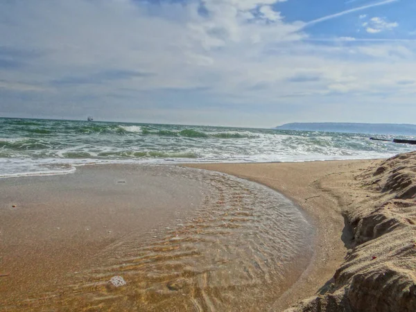 Güzel altın kum, arka planda bulut barındıran kristal deniz suyuyla doludur..