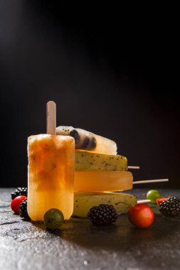 Böğürtlenli, böğürtlenli, kirazlı, böğürtlenli ve siyah arkaplanlı meyve buzlu fotoğraf.