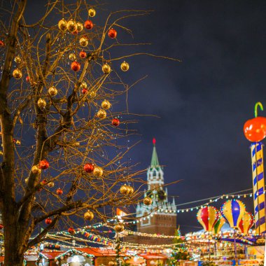 Arkaplanda yanan çelenklerle inşa edilmiş altın ve kırmızı topları olan Noel ağacı resmi