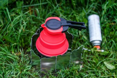 Turist ekipmanı konsepti. Çürütülebilir su kaynayan çaydanlık yanan sobanın üzerinde duruyor..