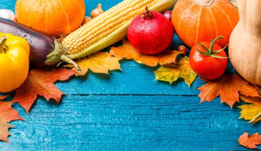 Sonbahar yaprakları, balkabağı, domates, nar, mavi ahşap masa üzerinde yer alan mısır resmi