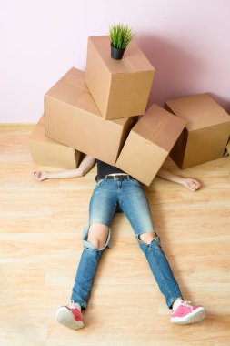 Kot pantolonlu bir kadının yeni dairede karton kutuların altında yattığı fotoğraf.
