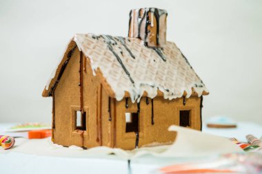 Beyaz arka plana serpiştirilmiş ev yapımı zencefilli kurabiye evi.