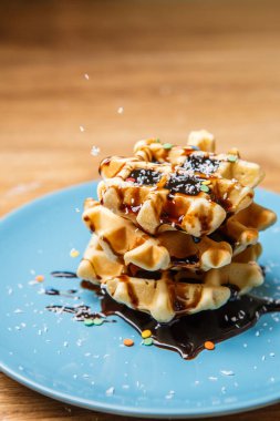 Ev yapımı waffle Çikolata ve hindistan cevizini mavi tabağa serpiyor