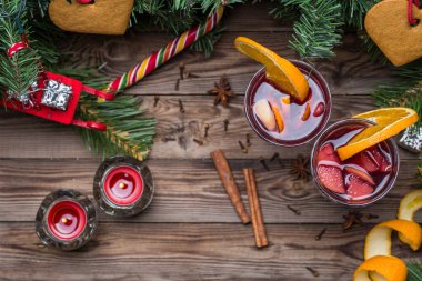 Portakallı, elmalı ve baharatlı iki bardak sıcak şarap. Düz uzanmış Noel arkaplanı.