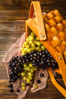 Üzüm resmi yeşil ve siyah. Stüdyoda, masanın üzerinde ahşap sepet içinde.