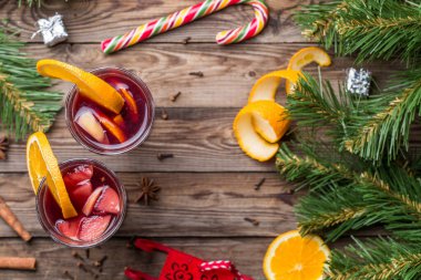 Portakallı, elmalı ve baharatlı iki bardak sıcak şarap. Düz uzanmış Noel arkaplanı.